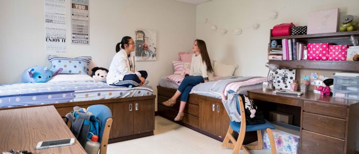 Two students sitting on beds in a double room in Hoben.